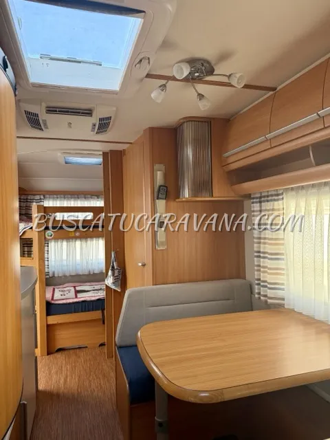 Interior caravana Fendt salón comedor con mesa madera y luz natural de Caravanas Fendt Saphir 495TFKM